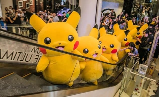 A line of Pikachu mascots riding a mall escalator