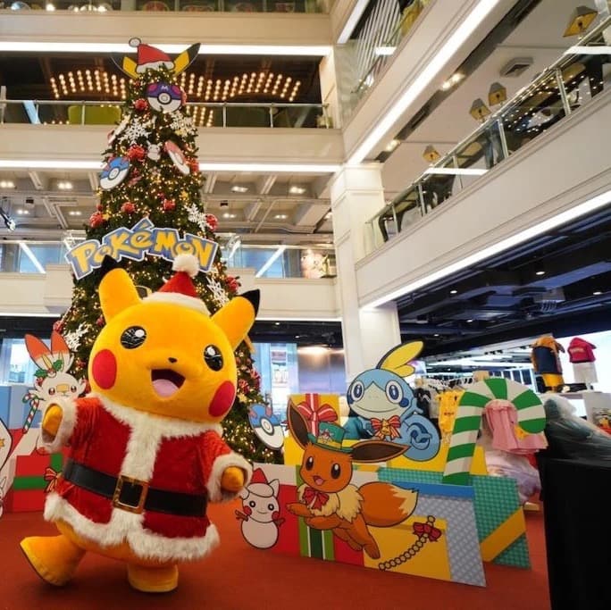 Santa Pikachu mascot in front of a Pok&eacute;mon Christmas tree