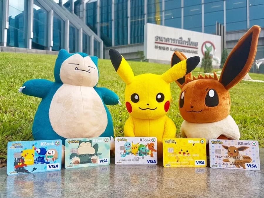 Pok&eacute;mon credit card designs with Snorlax, Pikachu and Eevee plush toys